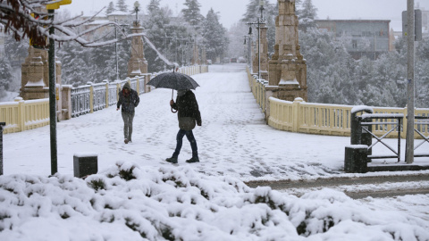 Dos personas caminan por una calle de Teruel, que hoy presentaba este aspecto debido a la nevada caída durante la pasada madrugada. EFE/Antonio García