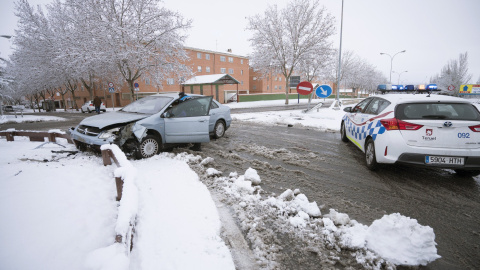 Un efectivo de la Policía Local asiste al conductor de un vehículo accidentado debido a la nieve acumulada hoy en Teruel. EFE/Antonio García