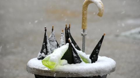 Varios paraguas rotos en una papelera, debido probablemente a los fuertes vientos que se registran hoy en Pamplona, ciudad sobre la que nieva intensamente desde primeras horas de la tarde. EFE/Villar López