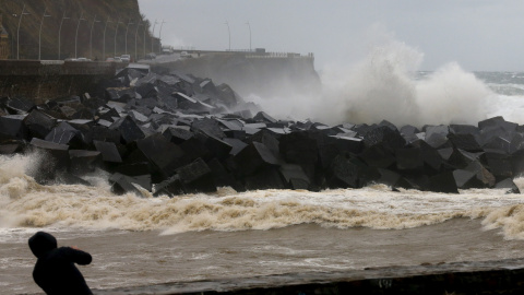 Un hombre toma fotografías del paseo Nuevo de San Sebastián, donde los cielos permanecen cubiertos con lluvias y chubascos generalizados. EFE/Juan Herrero.