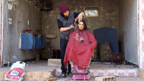 Un barbero le corta el pelo a un cliente fuera de su salón dañado por los rebeldes, en la ciudad de al-Ghariyah al-Gharbiyah town, Siria. REUTERS/Alaa Al-Faqir