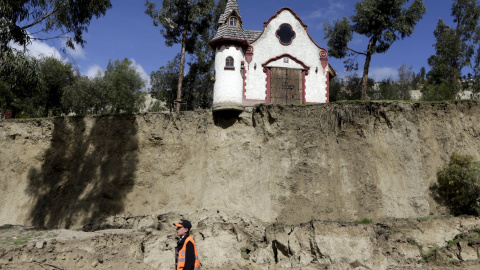 Un trabajador camina en frente de una capilla tras del deslizamiento de tierra producido por las fuertes lluvias en Jupapina, La Paz (Bolivia). REUTERS/David Mercado