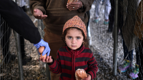 Una niña migrante recibe un sándwich en el campamento improvisado en la frontera entre Grecia y Macedonia, cerca del pueblo griego de Idomeni, el 2 de marzo de 2016, donde se encuentran miles de personas.AFP/LOUISA GOULIAMAKI
