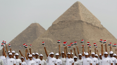 Los estudiantes de la Academia Militar egipcia sostienen banderas egipcias en la apertura del Campeonato Internacional de Paracaidismo, que está organizado por la Federación de Deportes Aéreos Egipcios (EPAF), frente a las grandes pirámides