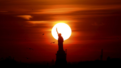 El sol se pone tras la estatua de la Libertad en el puerto de Nueva York. REUTERS/Brendan McDermid