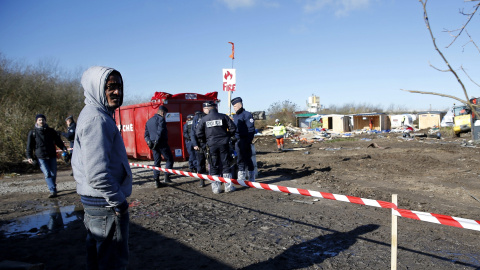 Un inmigrante permanece junto a varios policías antidisturbios de la Compañía Republicana de Seguridad (CRS) francesa durante el desmantelamiento del campo de refugiados de Calais, Francia.- EFE