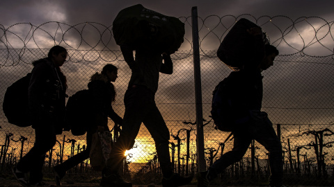 Varias personas cargan con sus enseres en el campo de refugiados de Gevgelija.- EFE