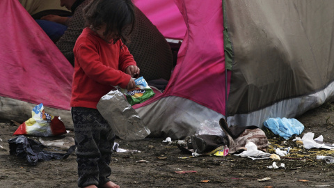 Una niña busca comida entre la basura en el campamento de refugiados de Idomeni, norte de Grecia.- EFE
