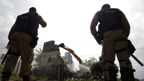 Guardias municipales observan la demolición de una casa en la comunidad Vila Autodromo de Río de Janeiro. REUTERS/Ricardo Moraes TPX IMAGES OF THE DAY