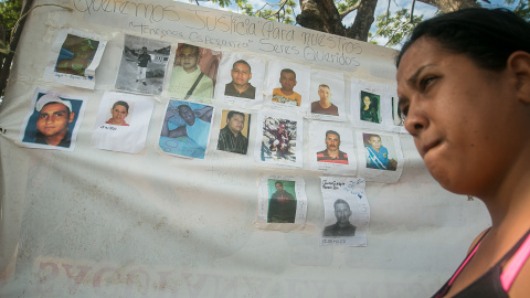 Una mujer camina junto a un cartel con fotografías de los mineros desaparecidos, hoy, miércoles 9 de marzo de 2016, en la localidad de Tumeremo, en el estado Bolivar, Venezuela. EFE/STR