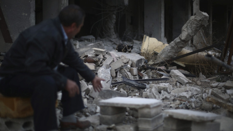 Un hombre da de comer a un gato entre los escombros en la zona de Jobar, al este de Damasco (Siria). EFE/Mohammed Badra