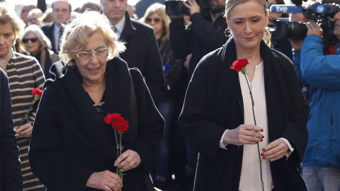 Cristina Cifuentes (d), y la alcaldesa de la capital, Manuela Carmena, durante el homenaje a las 193 personas asesinadas en los atentados yihadistas del 11 de marzo de 2004 esta mañana en la Estación de Atocha Cercanías.- EFE