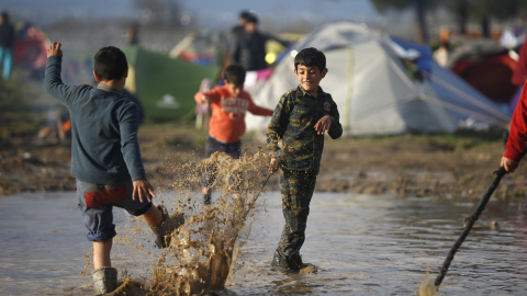 Niños migrantes juegan con el agua en un campamento improvisado inundado en la frontera entre Grecia y Macedonia, cerca de la localidad de Idomeni. REUTERS/Stoyan Nenov