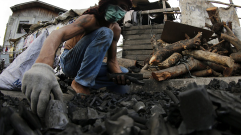 Un hombre recoge trozos de carbón vegetal para venderlos en en un puesto callejero en ciudad Las Pinas, al sur de Manila, Filipinas. EFE/Francis R. Malasig