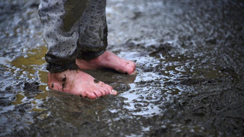 Un niño permanece en pie en el barro en un campo de refugiados cerca de Idomeni, Grecia. EFE/Nake Batev