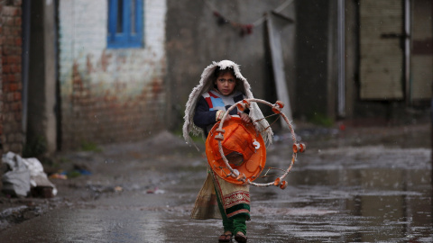Una chica lleva un tacatá por un callejón mientras llueve en Srinagar, 17 de marzo de 2016. REUTERS / Danish Ismail