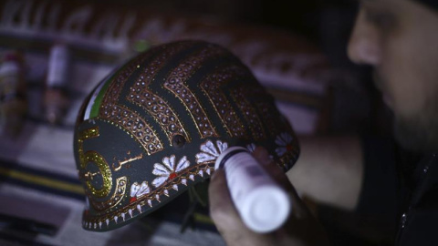 El artista sirio Akram Abo al-Foz mientras decora un casco militar en Douma, a 10 kilómetros al noreste de Damasco, Siria". EFE/Mohammed Badra