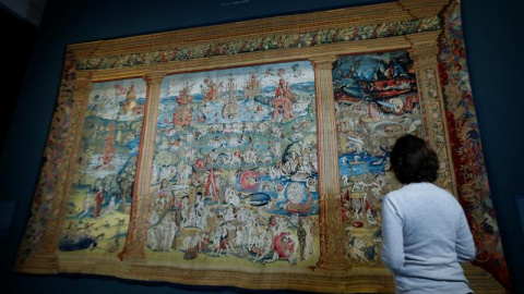 Una mujer objserva un tapiz con la obra 'El jardín de las Delicias' durante la presentación de la exposición 'El Bosco en El Escorial. Celebración del V Centenario', que muestra en el Monasterio de El Escorial once piezas dela rtista perten
