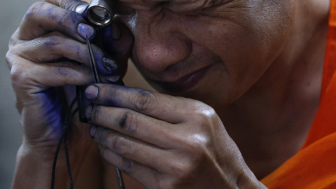 Un monje budista prepara sus herramientas antes de tatuar el cuerpo de un hombre en Bangkok. REUTERS/Chaiwat Subprasom
