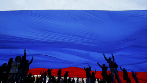 Personas sostienen una bandera nacional de Rusia durante el concierto festivo que marca el segundo aniversario de la anexión a Rusia de la región de Crimea, en el centro de Moscú. REUTERS/Maxim Shemetov