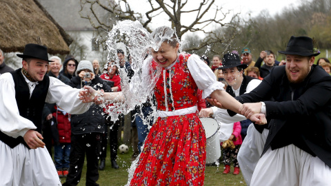 Un grupo de hombres lanzan a una mujer un cubo de agua como parte de la tradición de este 'Easter Break' en Szenna, Hungría. REUTERS/Laszlo Balogh