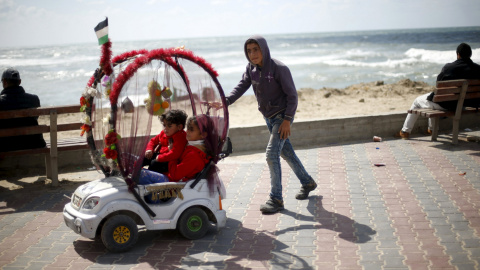Un niño palestino de 13 años alquila su coche de juguete para que los demás pequeños puedan disfrutan de un paseo en el puerto de la ciudad de Gaza. REUTERS/Mohammed Salem