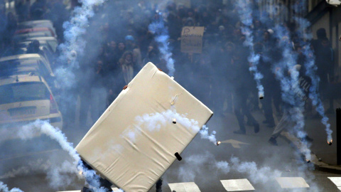 Unos jóvenes se protegen del gas lacrimógeno con un colchón durante los enfrentamientos con los antidisturbios en Nantes, Francia./ REUTERS/Stephane Mahe