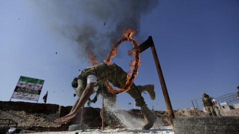 Un combatiente rebelde salta a través de un circuito de fuego como demuestra su habilidad durante una exhibición militar como parte de una ceremonia de graduación en un campamento en el norte de la provincia de Hama, Siria 31 de marzo de 20
