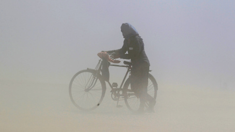Un hombre cubre su rostro mientras empuja una bicicleta durante una tormenta de arena junto al río Ganga, en Allahabad, India. /REUTERS-Jitendra Prakash