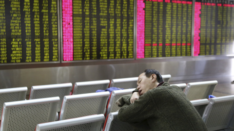 Un inversor duerme frente a la pantalla que muestra información sobre las acciones en una oficina de bolsa en Pekín. EFE/How Hwee Young