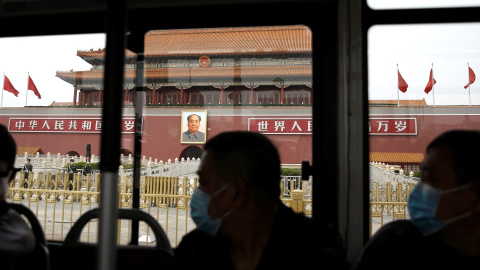Personas con mascarilla pasan en un autobús por delante de la Ciudad Prohibida, en la Plaza de TTiananmen, en Pekín.. REUTERS/Tingshu Wang
