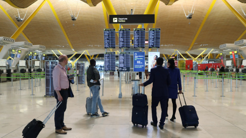 Varios pasajeros miran los paneles informativos de los vuelos en el aeropuerto de Barajas, en Madrid.. REUTERS/Susana Vera
