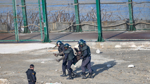 La guardia civil traslada a la fuerza a un migrante para su devolución en caliente a Marruecos tras saltar la valla de Ceuta el 30 de agosto de 2019.- CEAR/José Antonio Sempere