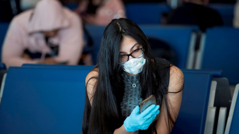23/03/2020 - Una joven con mascarilla mira el móvil. / EFE - ORLANDO BARRÍA
