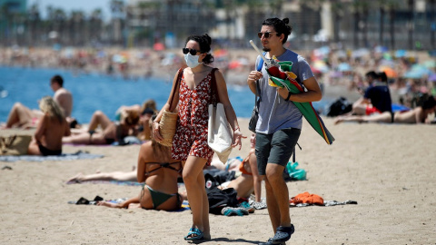 BARCELONA, 24/06/2020.- Dos personas llegan a la playa de la Barceloneta, tras la noche en la que se ha vivido una verbena de San Juan atípica por la pandemia de la COVID-19, en la que las playas de la ciudad han permanecido cerradas para e