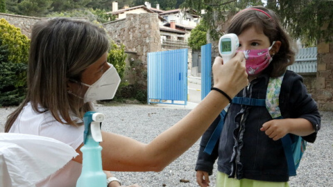 Una professora prenent la temperatura a una de les alumnes, a l'escola Els Ventets de Collsuspina, aquest dilluns. ACN