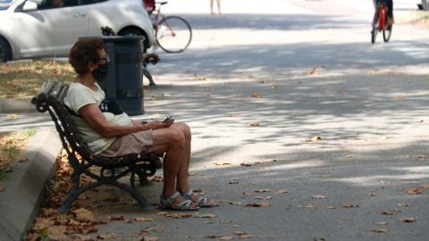 Una dona amb mascareta asseguda en un banc a Barcelona. ACN