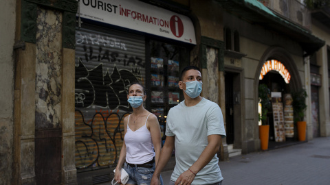 Una pareja pasa por delante de una oficina de turismo cerrada en Barcelona