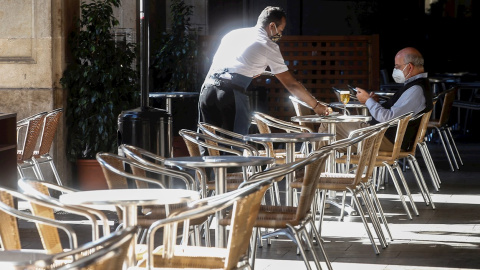 Un camarero atiende a un cliente, este miércoles, en un local de la Plaza Real de Barcelona. /EFE