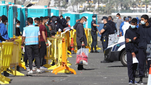 Varios inmigrantes llegados la pasada madrugada esperan este miércoles en el muelle de Arguineguín (Gran Canaria) a que les tomen las huellas dactilares y la filiación.