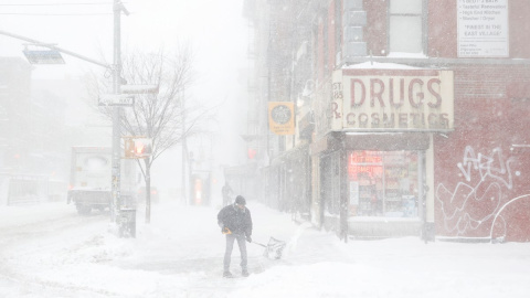 Un hombre trata de abrirse paso entre la nieve acumulada en una acera de Nueva York.