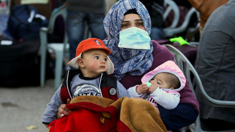 Una mujer sostiene a dos niños mientras abandona Gaza.