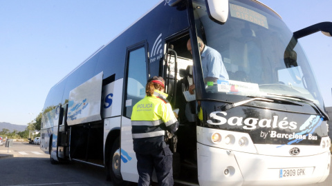Un Mosso controla la documentació d'un bus.