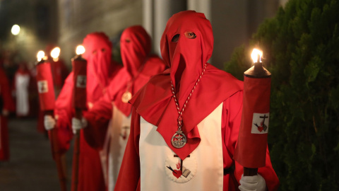 Nazarenos vestidos con túnica blanca y roja y capuz rojo durante una procesión en 2019.