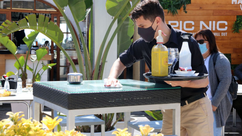 Un cambrer d'un restaurant de Sitges netejant la taula entre serveis d'aperitius. Imatge del 28 de març del 2021.
