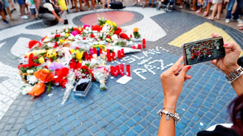 Una turista fotografía los ramos de flores y objetos de todo tipo depositados en el mural de Miro de La Rambla de Barcelona en recuerdo de los atentados en La Rambla y Cambrils. - EFE/Alejandro García
