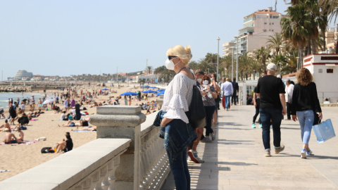 Una dona observa una de les platges de Sitges mentre passeja pel passeig. Imatge del 3 d'abril del 2021.