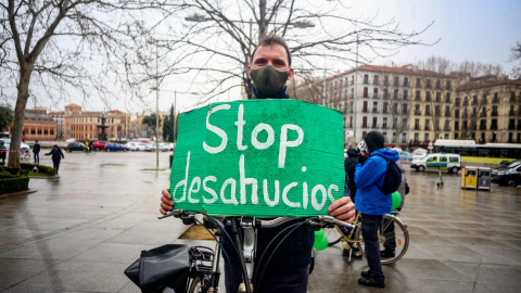 Un hombre con un cartel en el que se lee: `Stop desahucios´ en el final de la bicicletada durante una manifestación por el derecho a la Vivienda en Atocha, Madrid (España), a 21 de febrero de 2021.