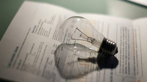Una bombilla junto a una factura de la luz.