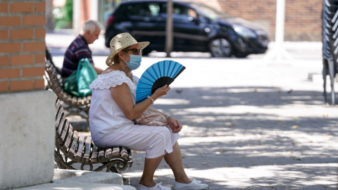Una anciana con mascarilla se abanica sentada en un banco en Madrid. E.P./A. Pérez Meca